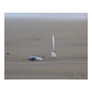 plastic fork sticking in sandy beach beside print