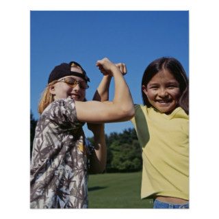 Smiling girls flexing biceps outdoors poster